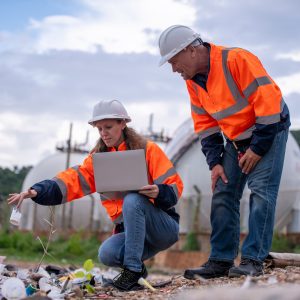 Environmental scientists or workers, wearing safety helmets and gloves, examining waste materials al